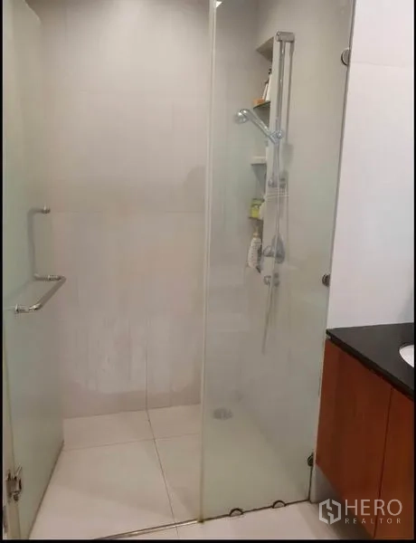 Condominium for rent in Sathon, Bangkok - Close-up of walk-in shower with sliding glass door and handheld showerhead.