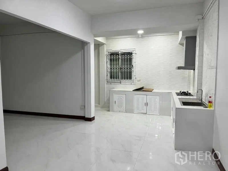 Townhouse for rent in Din Daeng, Bangkok - Open-plan area showing window with security bars beside the fitted kitchen.