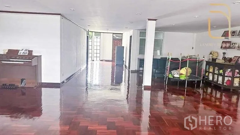 Detached House for sale in Huai Khwang, Bangkok - Large open-plan living area with glossy parquet wood floors, white walls, recessed lighting, and built-in cabinetry.