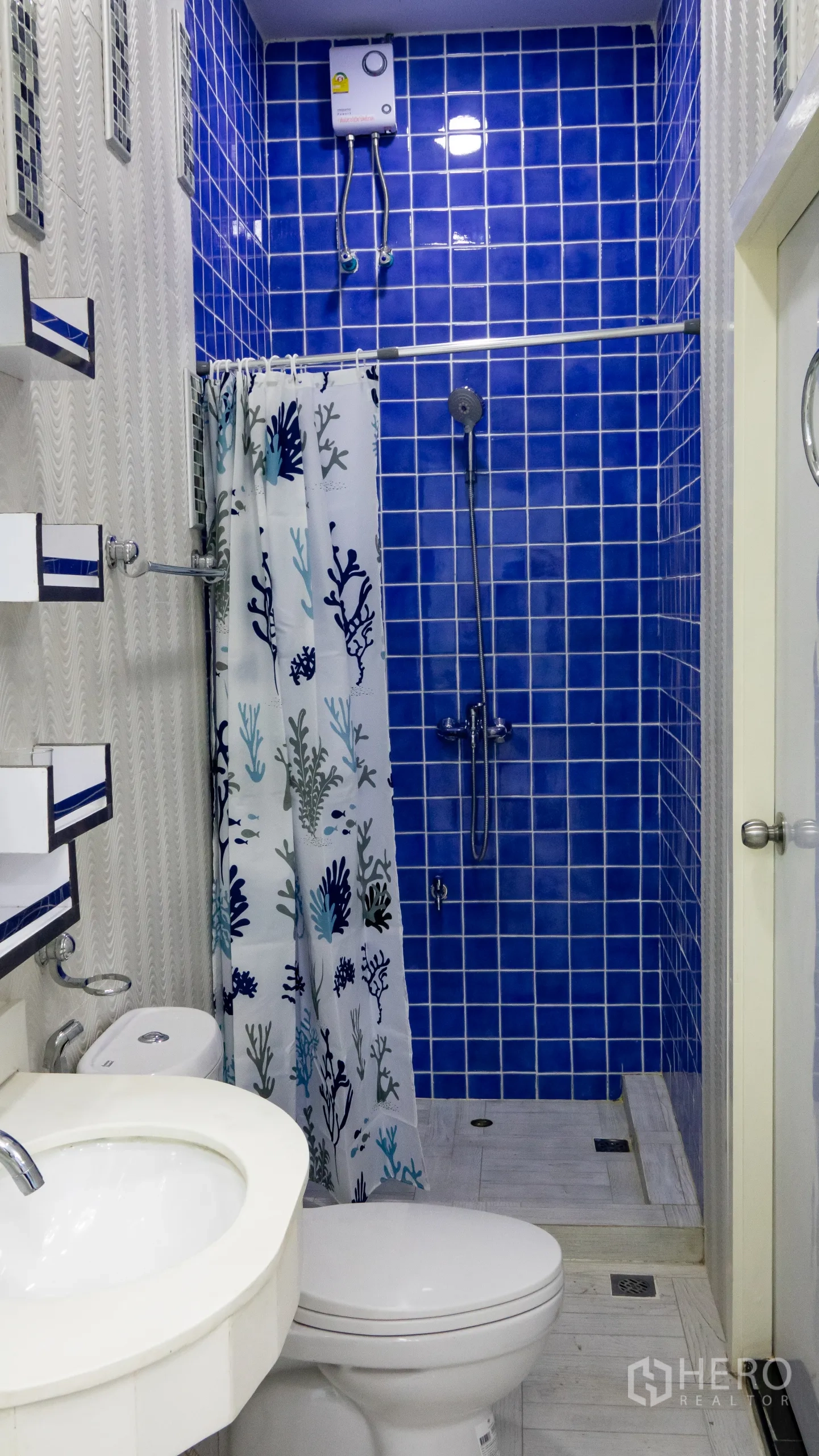 Condominium for rent or sale in Khlong Toei, Bangkok - Bathroom featuring a blue mosaic‑tiled shower, water heater and white fixtures.