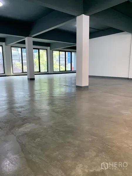 Shophouse for rent in Khlong Toei, Bangkok - Spacious commercial space with structural columns and large windows suited for showroom or dining area.