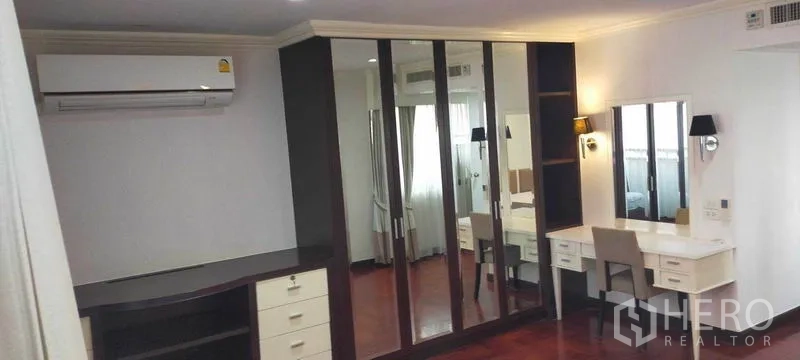 Condominium for rent in Watthana, Bangkok - Bedroom featuring mirrored wardrobes and a built-in vanity desk.