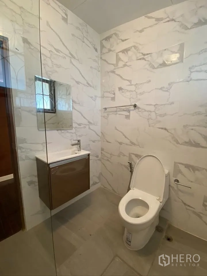 Detached House for rent in Suan Luang, Bangkok - Modern bathroom with marble-look tiles, vanity, and toilet.