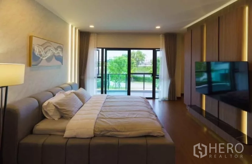 独立式住宅 出租或出售在Bang Phli, Samut Prakan - 主卧面向滑门阳台，灯光温馨。