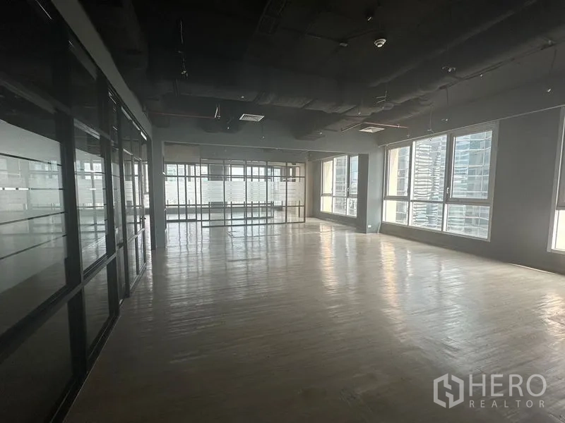 Office Space for rent in Bang Rak, Bangkok - Bright corner workspace with multiple windows and a dark ceiling.