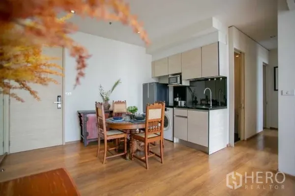 Condominium for sale in Khlong Toei, Bangkok - View of kitchenette with light cabinetry, black backsplash, and hallway to bedrooms.
