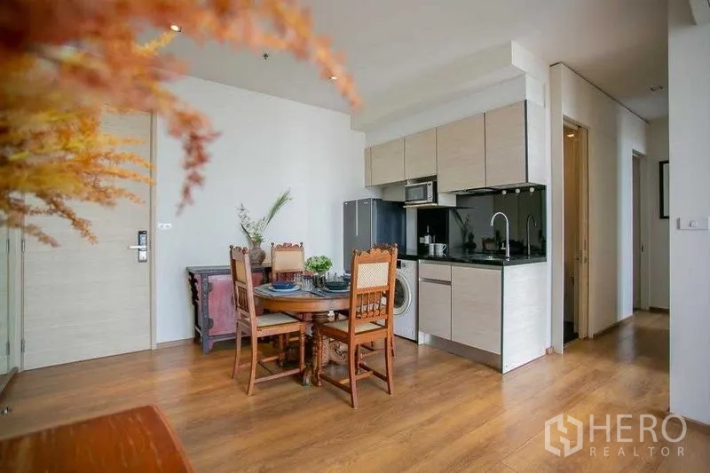Condominium for sale in Khlong Toei, Bangkok - View of kitchenette with light cabinetry, black backsplash, and hallway to bedrooms.