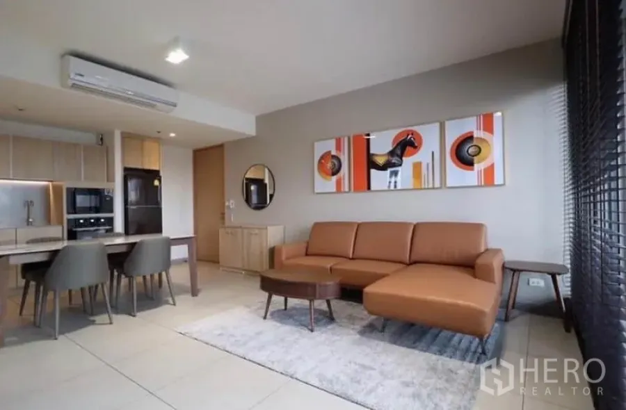 公寓 出租在Watthana, Bangkok - 开放式客厅，棕色皮沙发、茶几，与厨房相连并有大窗户。