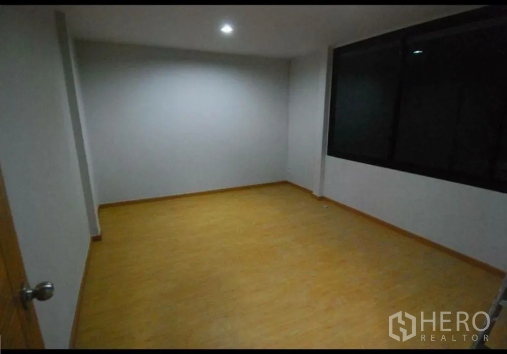Home Office for rent in Lat Phrao, Bangkok - Flexible bedroom or office room with wood-look flooring and a large window.