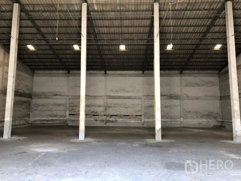 货栈 出租在Lat Krabang, Bangkok - 仓库内部宽敞，高挑屋顶，钢桁架与混凝土地面，中间立柱与顶部照明。