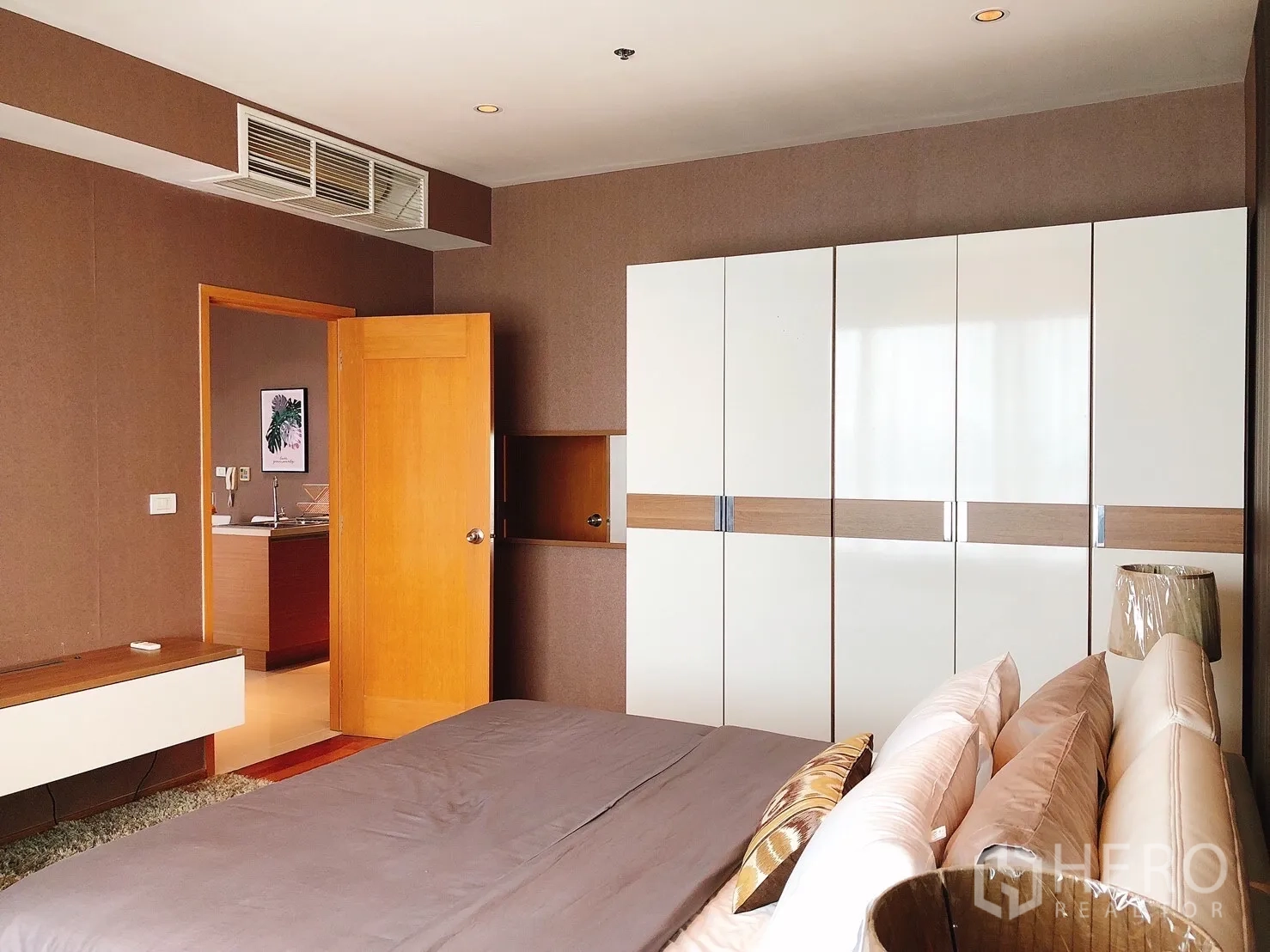 Condominium for rent in Khlong Toei, Bangkok - Bedroom with large built-in wardrobes and doorway to the living area.