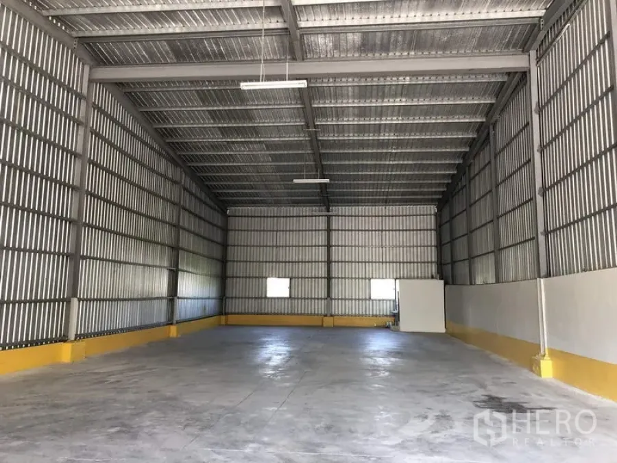 Warehouse for rent in Lat Krabang, Bangkok - Spacious warehouse interior with high steel roof, concrete floor, two small windows and bright strip lighting in Lat Krabang, Bangkok.