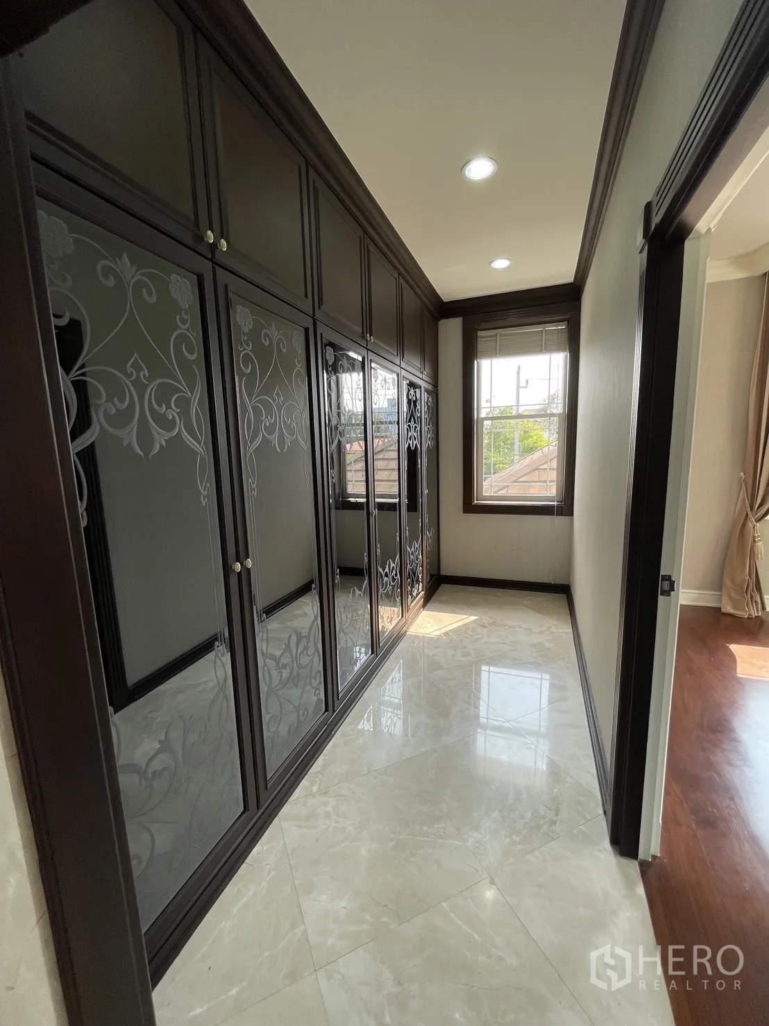 Detached House for rent in Chatuchak, Bangkok - Walk-in closet corridor with dark built-in wardrobes and marble floor.