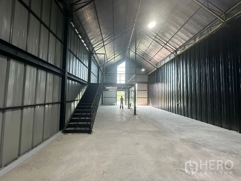 Warehouse for rent in Bueng Kum, Bangkok - Central aisle view toward tall front windows with a staircase up to the mezzanine platform.