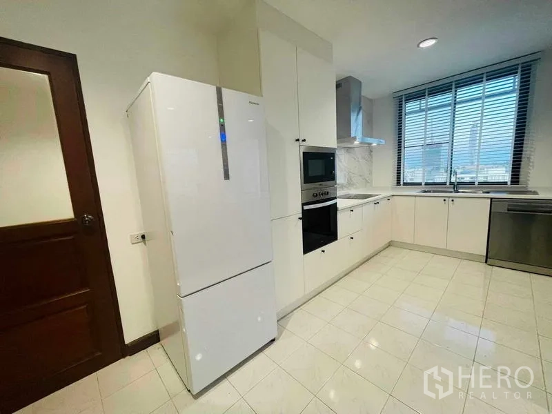 Condominium for rent - Bright kitchen with tall refrigerator, built-in oven, and cabinets.