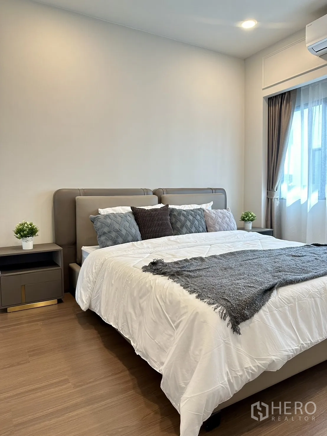 Detached House for rent or sale - Airy bedroom with king bed, bedside tables, wood flooring and window with drapes.