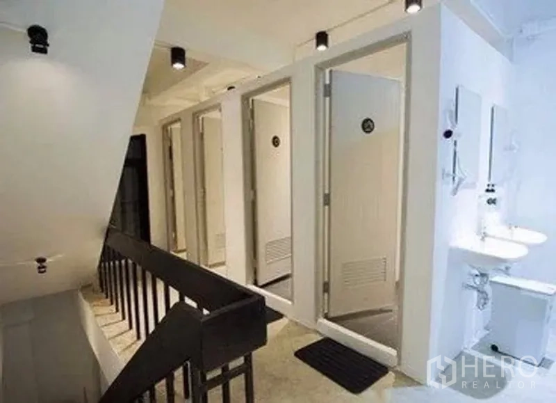 Retail Space for rent in Khlong Toei, Bangkok - Bright corridor with multiple shower and restroom stalls and wall-mounted sinks.