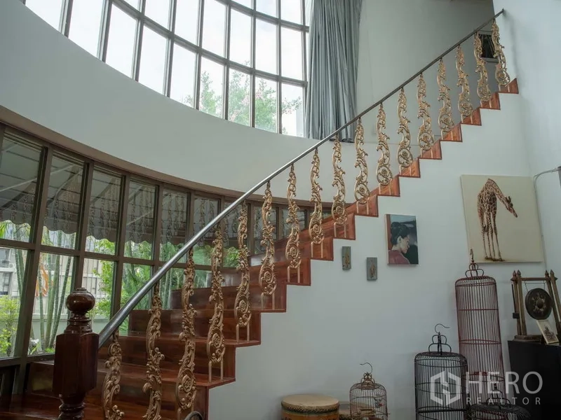 อพาร์ทเมนท์ for rent in Khlong Toei, Bangkok - บันไดไม้โค้งพร้อมราวลูกกรงลายทองและหน้าต่างสูงโปร่ง.