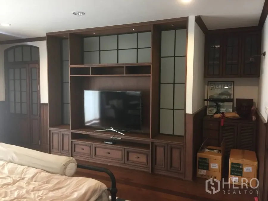 Townhouse for sale in Suan Luang, Bangkok - Living area with custom dark-wood TV cabinet and shelving.
