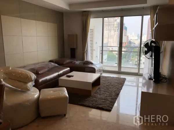 公寓 出租在Khlong Toei, Bangkok - 客厅配皮沙发与电视柜，落地推拉门通往阳台