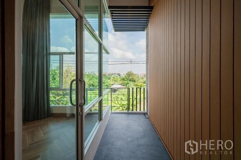 联排别墅 出售在Lat Phrao, Bangkok - 狭长覆盖式阳台，玻璃墙，远眺城市与绿地。