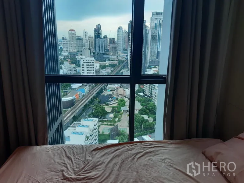 Condominium for rent or sale in Khlong Toei, Bangkok - Bedroom window framing city skyline and elevated rail track view.