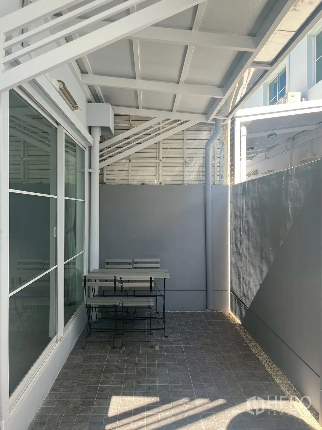 联排别墅 for rent in Prawet, Bangkok - 后部带顶露台，瓷砖地面与户外桌椅。