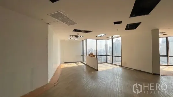 Office Space for rent or sale - Bright corner office with floor-to-ceiling windows and unfinished ceiling panels.