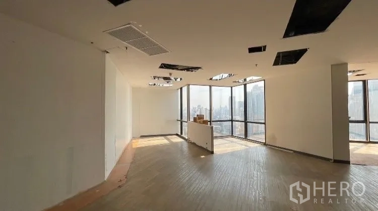 Office Space for rent or sale - Bright corner office with floor-to-ceiling windows and unfinished ceiling panels.