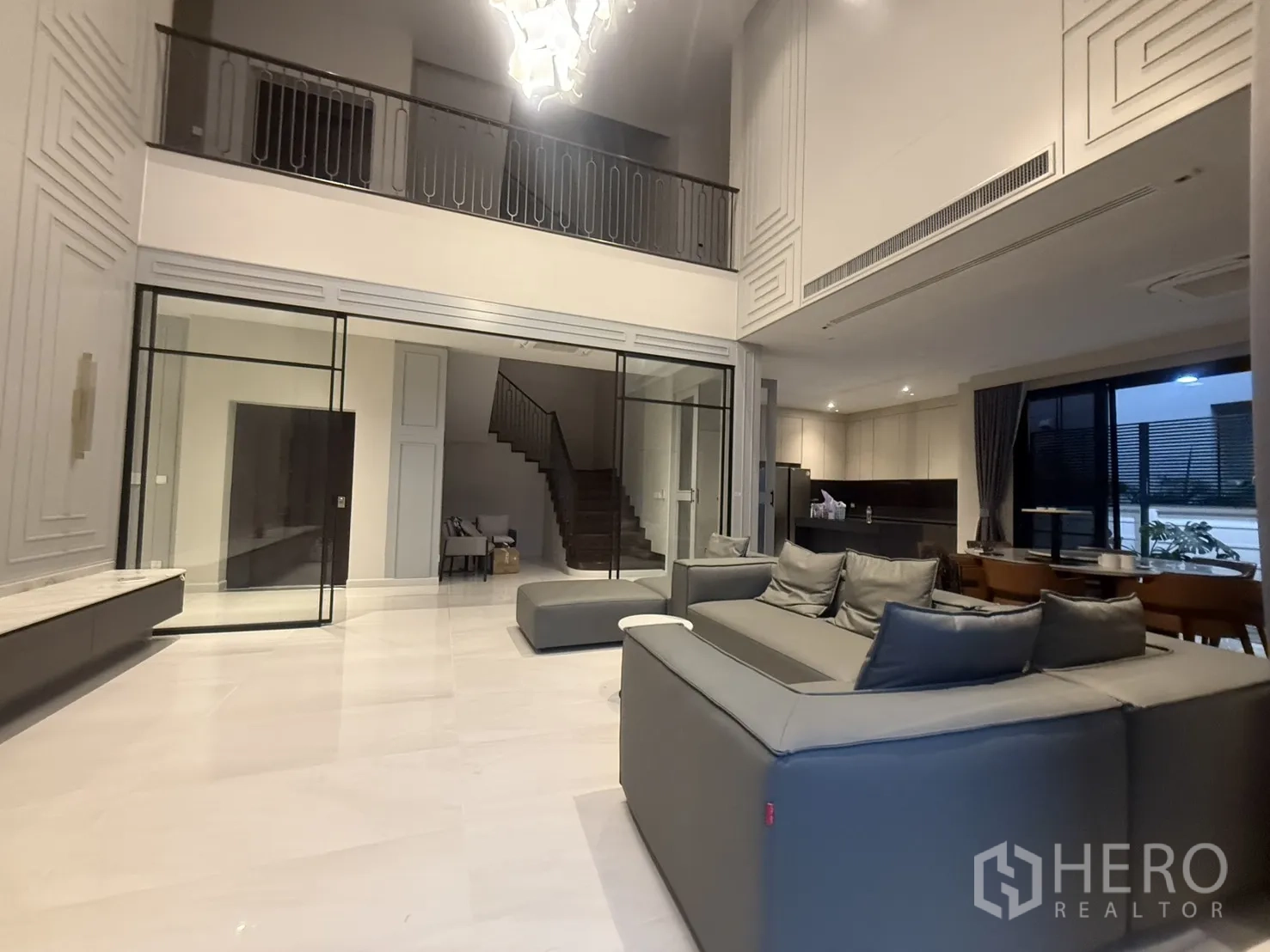 Detached House for rent in Saphan Sung, Bangkok - Double-height living room with chandelier, glass partitions and open kitchen.