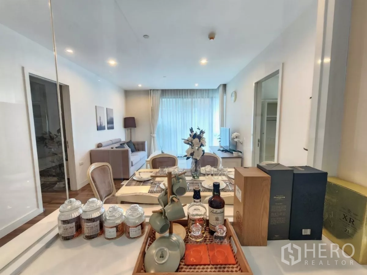 Condominium for rent in Phra Khanong, Bangkok - Kitchen counter view toward the dining and living areas with a decorative bar setup.