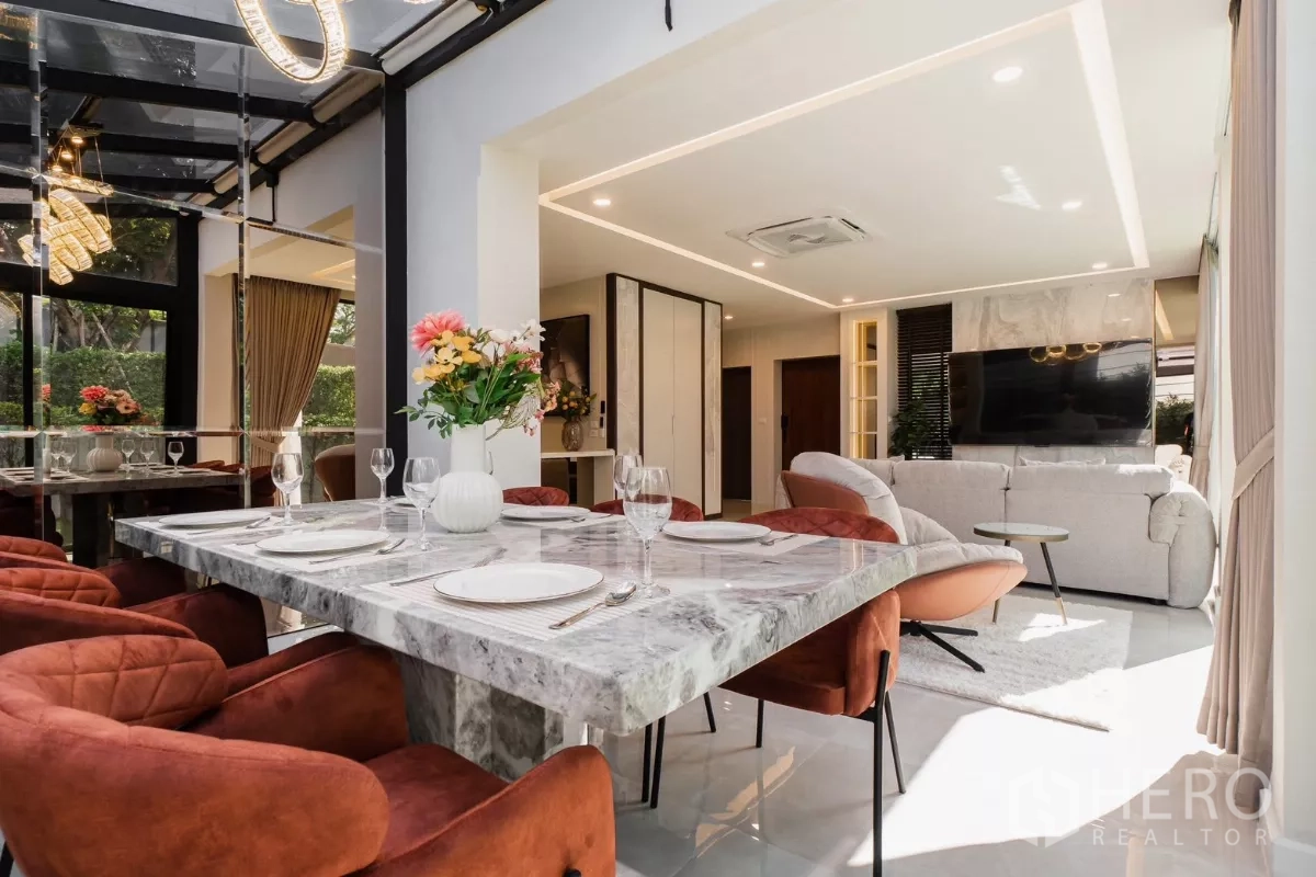 Detached House for rent or sale in Prawet, Bangkok - Marble dining table and velvet chairs in glass-roof conservatory beside living room