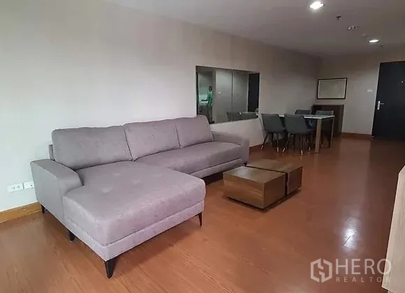คอนโด ให้เช่าในHuai Khwang, Bangkok - ห้องนั่งเล่นกว้าง โซฟารูปตัวแอลสีเทา พื้นไม้ โต๊ะกลาง และมุมรับประทานอาหาร