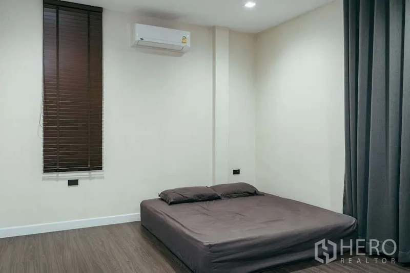 Detached House for sale in Sai Mai, Bangkok - Simple bedroom with platform bed, air conditioner and blackout curtains.