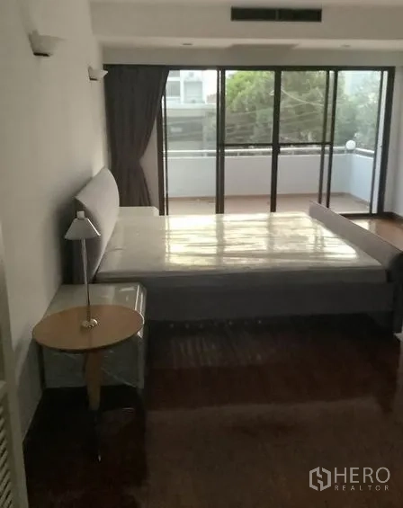 联排别墅 出租在Khlong Toei, Bangkok - 卧室通向阳台，落地玻璃门与外部绿意