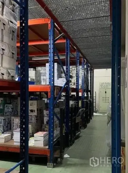 Warehouse for sale in Bangkok Yai, Bangkok - Warehouse aisle with steel pallet racking and safety mesh overhead.