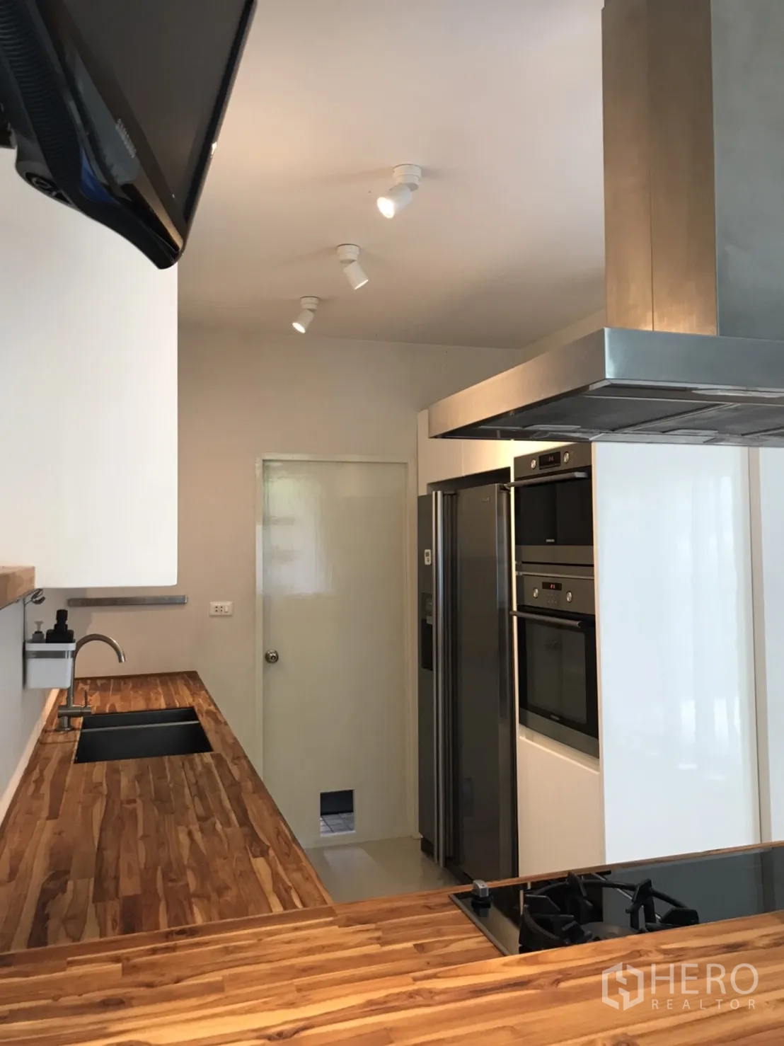 Detached House for rent or sale in Saphan Sung, Bangkok - Kitchen with wooden countertops, built-in ovens and a double-door refrigerator.