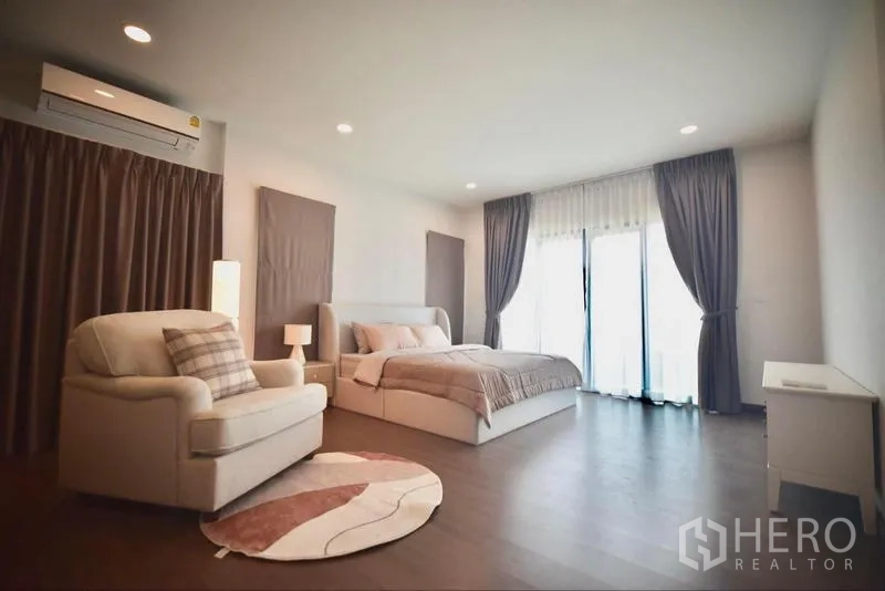 Detached House for rent in Bang Phli, Samut Prakan - Expansive master bedroom with seating area and balcony doors.