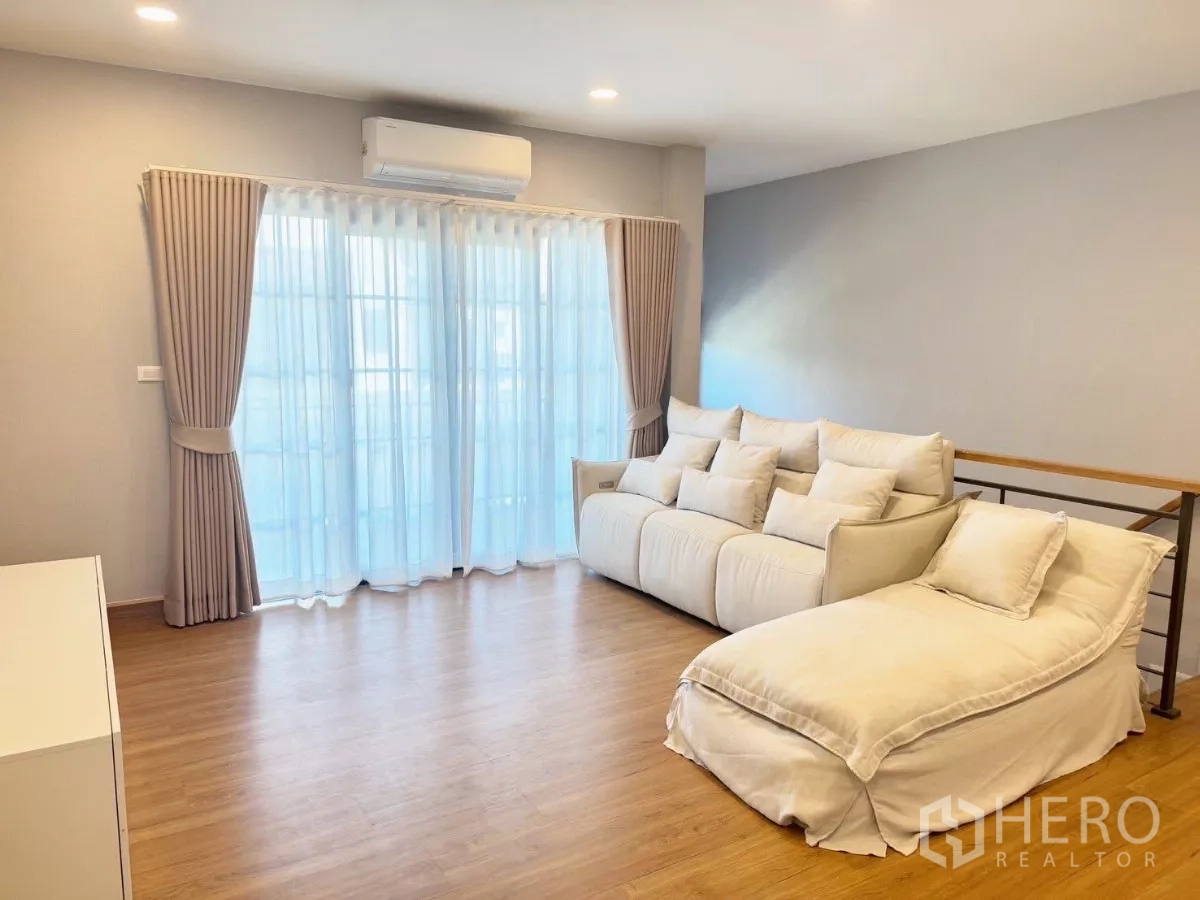 Detached House for rent or sale in Bang Phli, Samut Prakan - Upstairs family room with sofa set, wood flooring and balcony doors.
