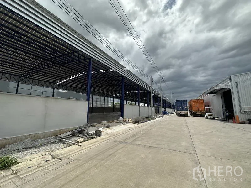 货栈 出租在Lat Krabang, Bangkok - 仓库对面的带顶装卸棚，宽敞混凝土地坪与完善排水便于车辆流转。