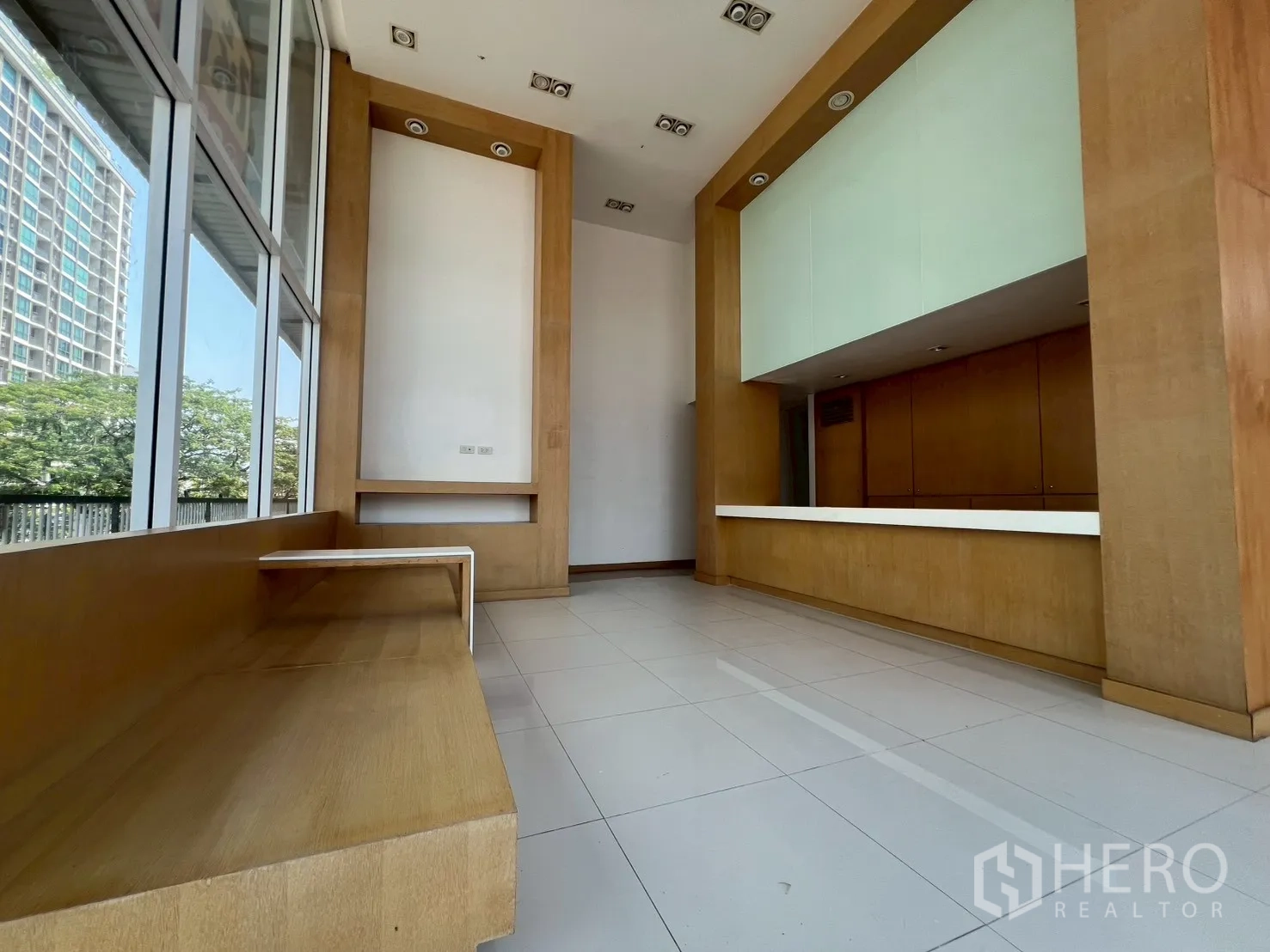 พื้นที่ขายของ for rent in Watthana, Bangkok - โถงต้อนรับเพดานสูง พื้นกระเบื้องสีขาว เคาน์เตอร์ต้อนรับยาว และที่นั่งบิวท์อินข้างหน้าต่างกระจกสูง