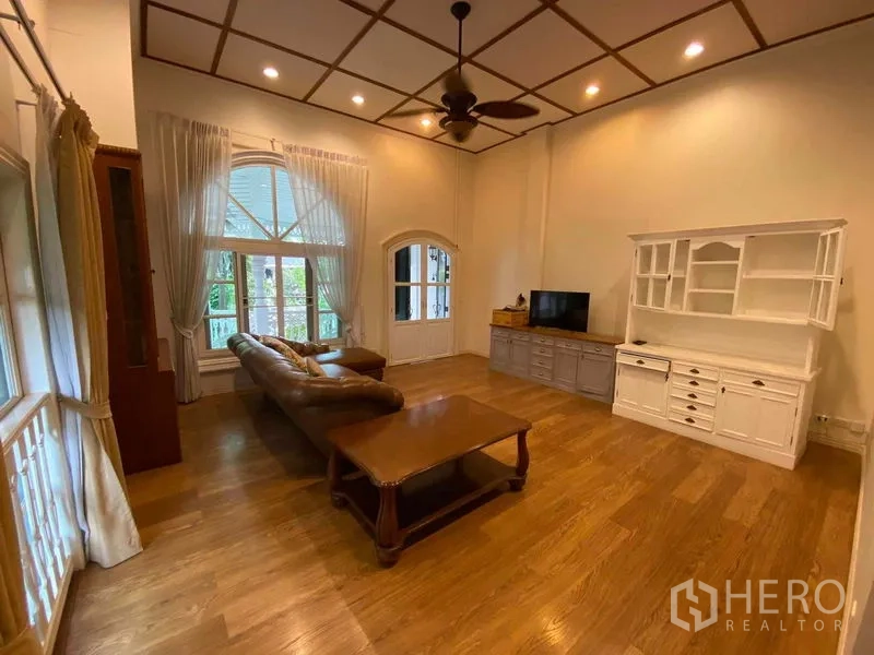 Townhouse for rent or sale in Mueang Samut Prakan, Samut Prakan - Living room with high ceiling, arched window, leather sofa and TV cabinet.