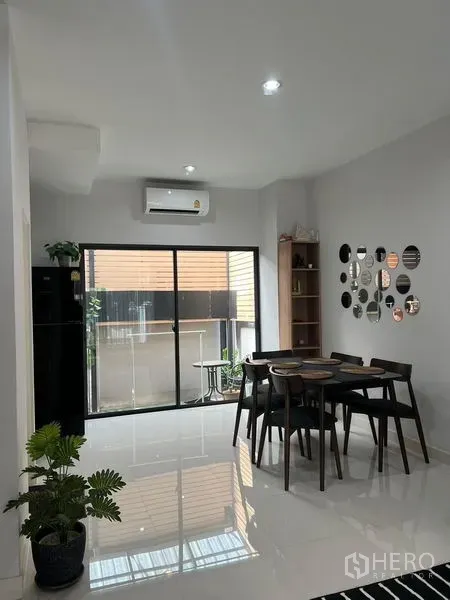Townhouse for rent in Saphan Sung, Bangkok - Open dining area with table for four, glossy white floors and sliding glass doors to a small patio.