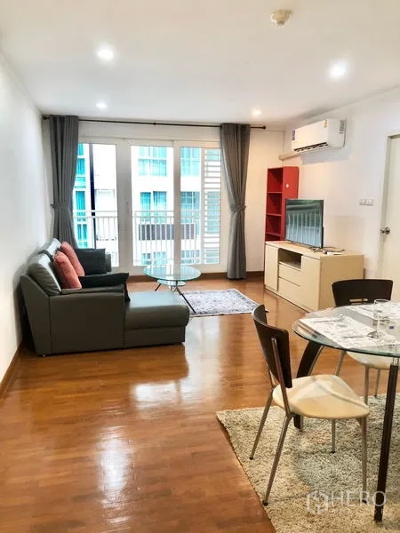公寓 出租或出售在Watthana, Bangkok - 曼谷公寓明亮客餐厅，灰色沙发、玻璃茶几、电视柜与通阳台的落地门