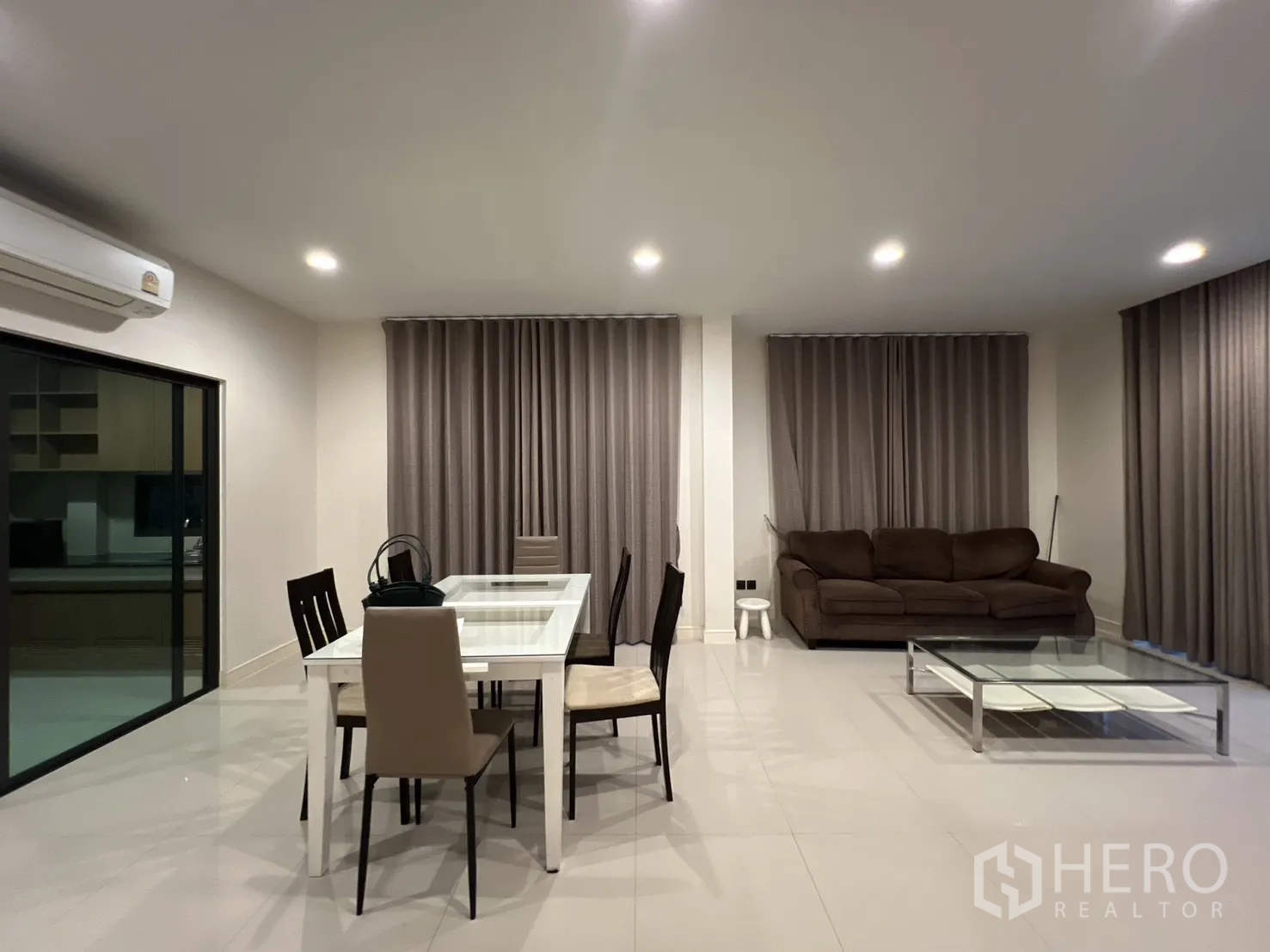 Detached House for rent or sale in Bang Kapi, Bangkok - Dining area beside a sofa set with sliding door to the kitchen.