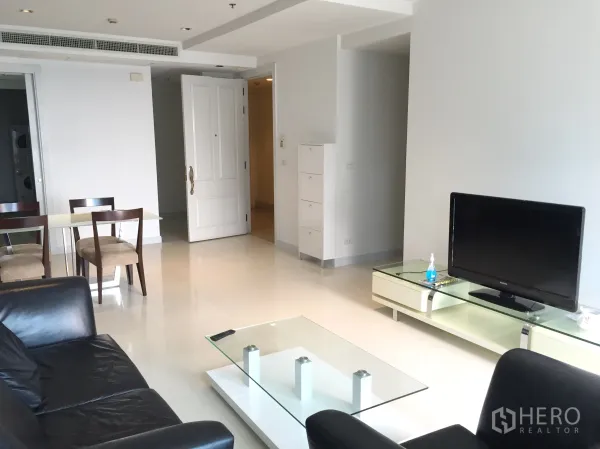 公寓 出租在Pathum Wan, Bangkok - 明亮客厅，黑色皮沙发、电视柜与玻璃茶几。