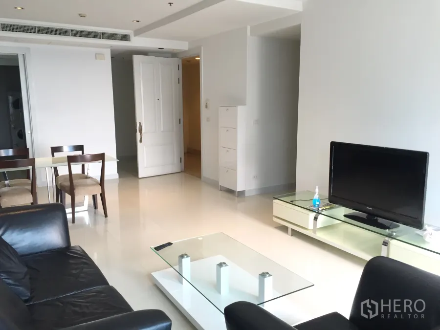 公寓 出租在Pathum Wan, Bangkok - 明亮客厅，黑色皮沙发、电视柜与玻璃茶几。