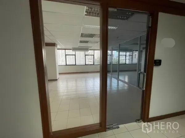 Office Space for rent in Khlong Toei, Bangkok - Glass door entry to an office with city-view windows and internal glass partitions.