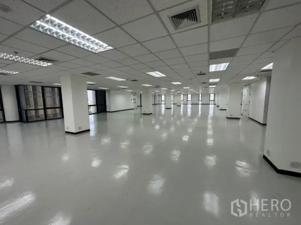 办公空间 出租 - 宽阔办公楼层，荧光灯格栅吊顶与环幕式窗带。