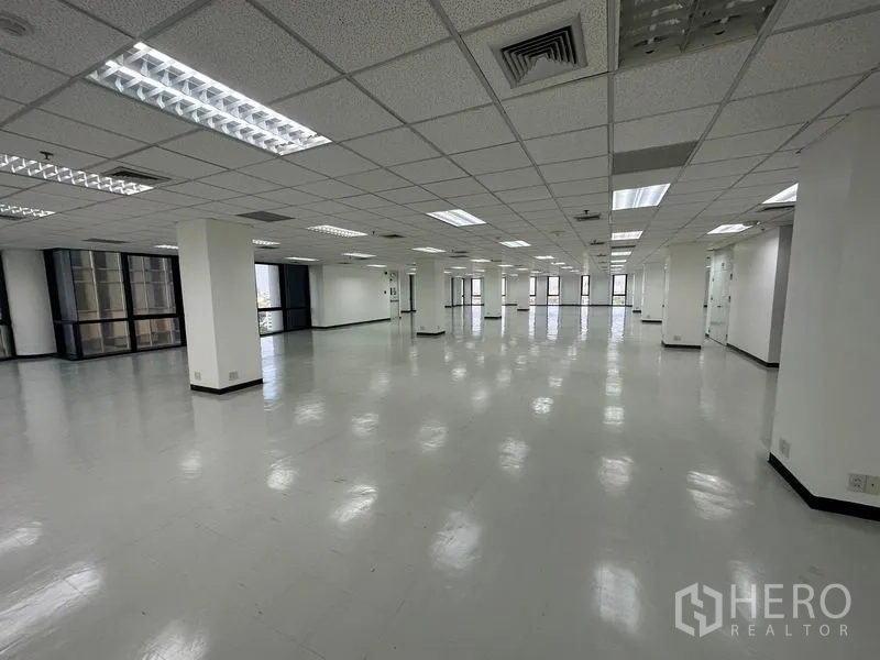 办公空间 出租 - 宽阔办公楼层，荧光灯格栅吊顶与环幕式窗带。